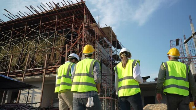 Civil engineers and construction workers meeting at construction site.