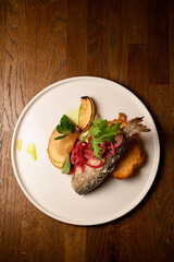 top view of plate of fried fish garnished with onion and lemon and toast