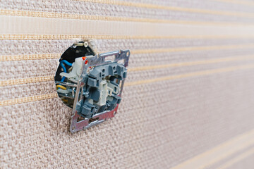  replaces or repairs the light switch on the wall with brown wallpaper.