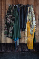 Boots and oilskins hanging on a coat rack on a wooden wall