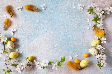 Easter decorative background with flowering cherry plum branches and feathers, space for congratulations text.