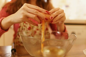 Close-up shot of making cookies while breaking eggs into a bowl. Detail photo with only hands visible when breaking eggs.