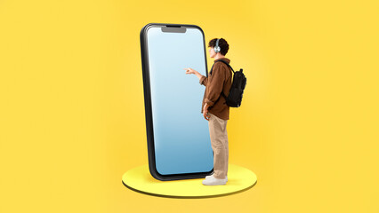 Male Student Using Large Smartphone With Blank Screen, Yellow Background