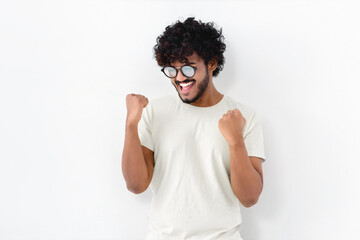Happy ecstatic cheerful Asian man with curly hair in white t-shirt and glasses shouting yeah...