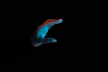 Black female hand holding invisible object, showing small amount of something, black background with neon lights