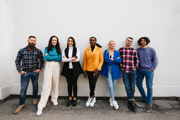 Obraz premium Mixed race group of stylish people standing in a row against a wall looking at camera. Copy space.