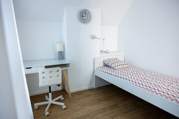 Modern interior of a cozy bedroom with the slanted ceiling