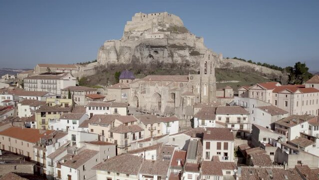 Lateral aerial view of the gothic Archpriest Church of Santa Maria of Morella with its ancient castle as background, Spain. 