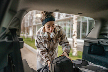 one young woman pack luggage baggage suitcase in the trunk of the car