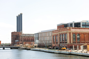 Naklejka premium An abandoned old brick manufacturing factory building stands tall with broken windows and overgrown vegetation, showcasing the industrial heritage of a bygone era