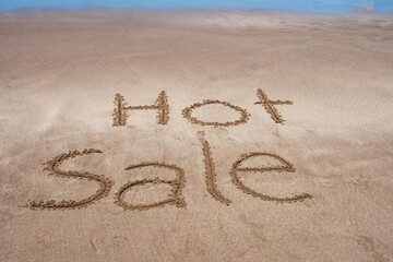 Hot Sale written in the sand of the beach on the seashore.