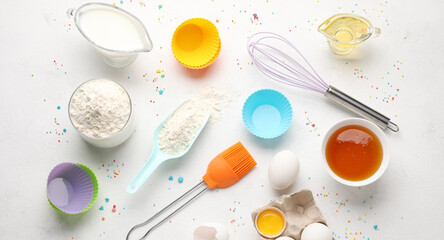 Different ingredients and utensils for baking muffins on light background