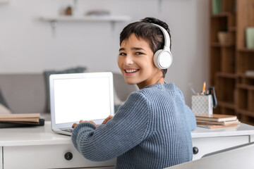 Little boy in headphones using laptop at home