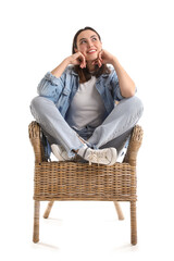 Young woman sitting in wicker armchair on white background