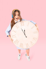 Little girl with big wall clock on pink background