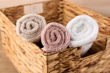 Fototapeta na wymiar Wicker basket with rolled cotton towels on wooden table