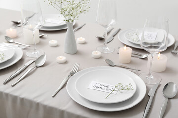 Setting for Mother's Day celebration with gypsophila flowers and burning candles on table