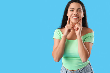 Beautiful young woman smiling on blue background