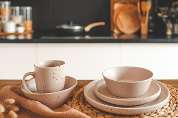 Set of beige minimalist dishes on a table against the backdrop of a kitchen