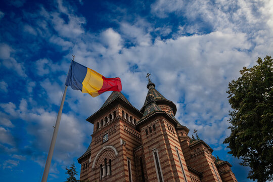 Romanian flag in front Timisoara Metropolitan Cathedral, or Catedrala Mitropolitana, with blue. The Metropolitan Cathedral is the main romanian orthodox church of Timisoara, Romania, belonging to the 