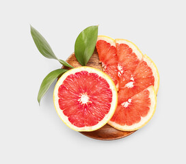 Plate with pieces of ripe grapefruit and plant branch on white background