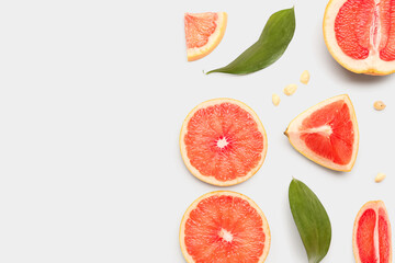 Composition with pieces of ripe grapefruit, seeds and plant leaves on white background