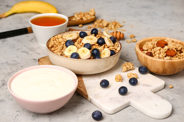 Bowls with tasty granola and yogurt on grunge background