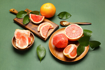 Composition with ripe grapefruits and plant leaves on green background