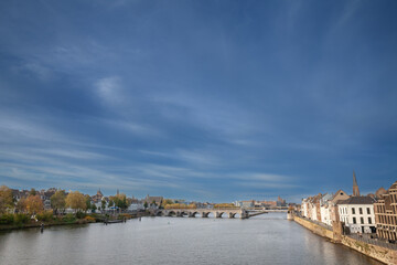 Fototapeta premium Panorama of Maastricht Waterfront on the Meuse Maas river with a focus on sint servaasbrug or saint servatius bridge, in autumn, during a sunny afternoon. Maastricht is a dutch city in the netherlands