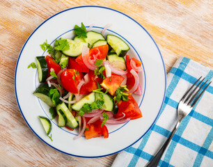 Delicious summer salad of cucumbers and tomatoes on a plate