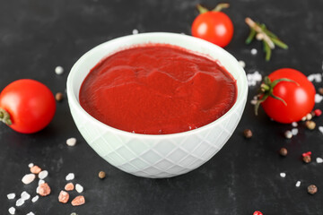 Bowl of tasty tomato paste and salt on black grunge background