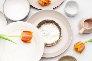 Composition with different clean dishes and tulip flowers on white background