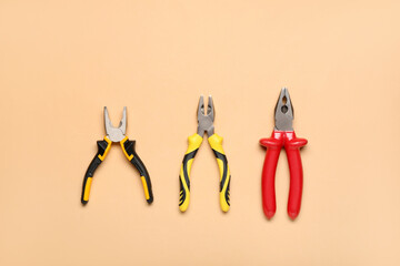 Different pliers on beige background