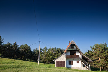 Residential house, a mountain chalet building, called vikendica, in the middle of a grass field meadow in the Balkans in Divcibare, Serbia, one of the Serbian ski resorts.