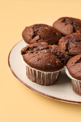 Plate with tasty chocolate cupcakes on beige background, closeup