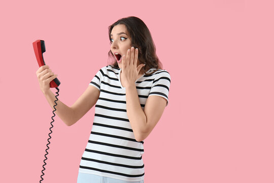 Shocked young woman with phone receiver on pink background