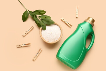 Laundry detergents, clothespins and plant branch on beige background