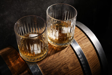 Barrel with glasses of cold whiskey on dark background