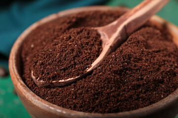 Bowl with spoon of coffee powder on green table, closeup