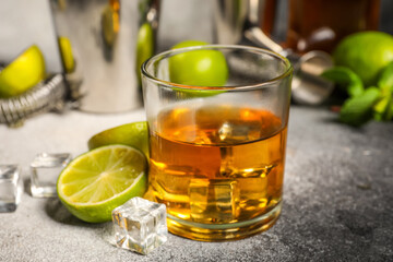 Glass of rum with ice, mint and lime on grey background