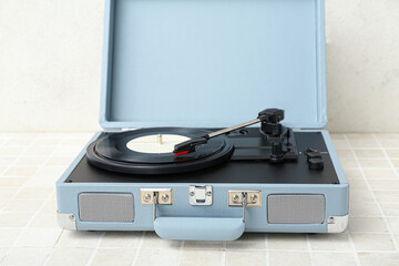 Obraz premium Record player with vinyl disk on table near light wall