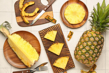 Wooden board with cut pineapple on light background