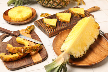 Wooden board with cut pineapple on light background
