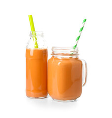 Mason jar and bottle of tasty orange smoothie with straws on white background