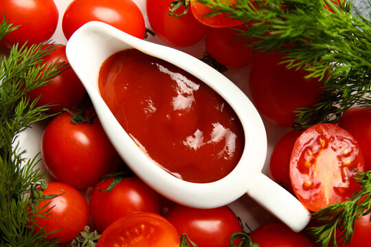 Gravy boat with tasty ketchup and fresh vegetables on table, closeup