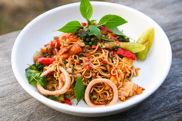 noodles plate with instant noodles stir fried with vegetables herb spicy tasty appetizing asian noodles mix seafood stir fried squid with basil and chilli pepper - 585587432