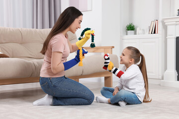 Happy mother and daughter playing with funny sock puppets together at home