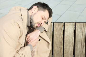 Obraz premium Tired man sleeping on bench outdoors. Space for text