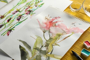 Beautiful floral pictures and watercolor paints on yellow wooden table