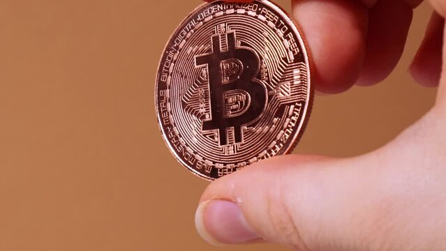 Female hands holding Bitcoin gold coin. Bitcoin mining trading concept. BTC golden money spinning around. Worldwide virtual internet Cryptocurrency or crypto digital payment system. Digital coin money
